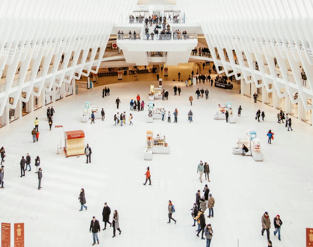 Wooden shelf with gray and olive drab green baseball caps, next to wooden clothes hanger with sweaters.